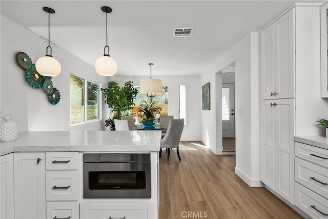 kitchen with white cabinets, plenty of natural light, visible vents, and light wood-style floors