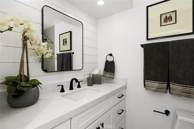 bathroom with toilet, vanity, and recessed lighting
