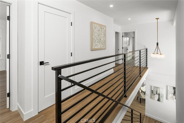 stairway with baseboards, wood finished floors, and recessed lighting