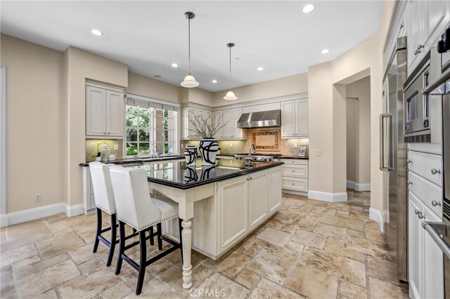 1489 Caballero Rd, Arcadia, CA 91006 - kitchen featuring stone tile floors, dark countertops, wall chimney range hood, backsplash, and recessed lighting
