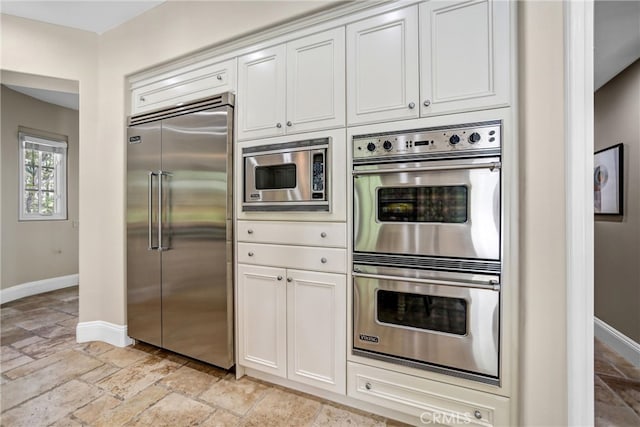 1489 Caballero Rd, Arcadia, CA 91006 - kitchen featuring built in appliances, stone tile floors, and white cabinetry