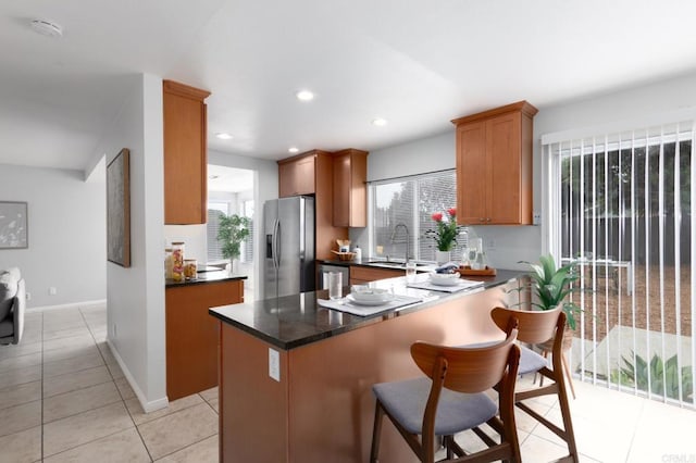 992 Churrituck Dr, San Diego, CA 92154 - kitchen featuring a kitchen bar, stainless steel refrigerator with ice dispenser, dark countertops, light tile patterned floors, and a sink