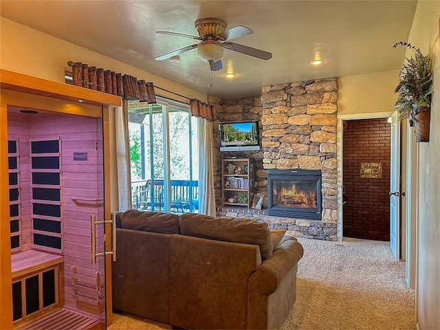 living area featuring carpet flooring, ceiling fan, and a fireplace