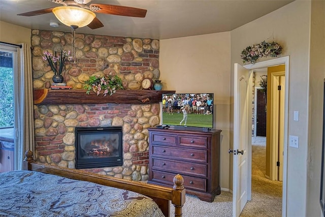 carpeted bedroom featuring a ceiling fan and a large fireplace