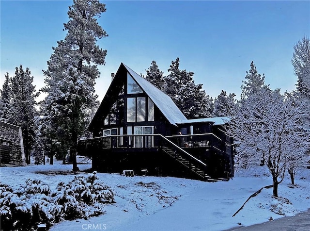 snow covered back of property featuring a wooden deck and stairs