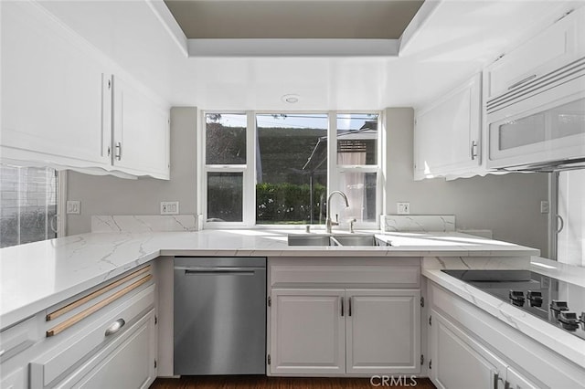 kitchen with stainless steel dishwasher, black electric stovetop, white microwave, white cabinetry, and a sink