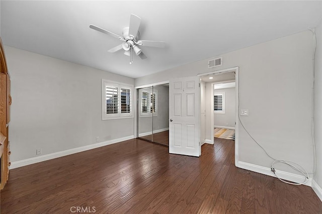unfurnished bedroom featuring a ceiling fan, baseboards, wood finished floors, visible vents, and a closet