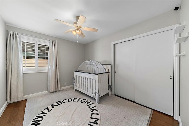 bedroom with a closet, a ceiling fan, baseboards, and wood finished floors