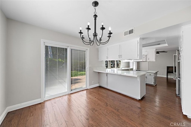 kitchen featuring visible vents, light countertops, baseboards, a peninsula, and a chandelier