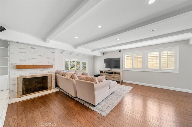 living room with baseboards, a fireplace with raised hearth, recessed lighting, and wood finished floors