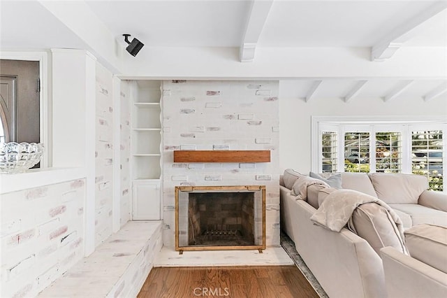 living room with a fireplace, beam ceiling, and wood finished floors