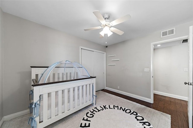 bedroom featuring baseboards, a closet, wood finished floors, and visible vents