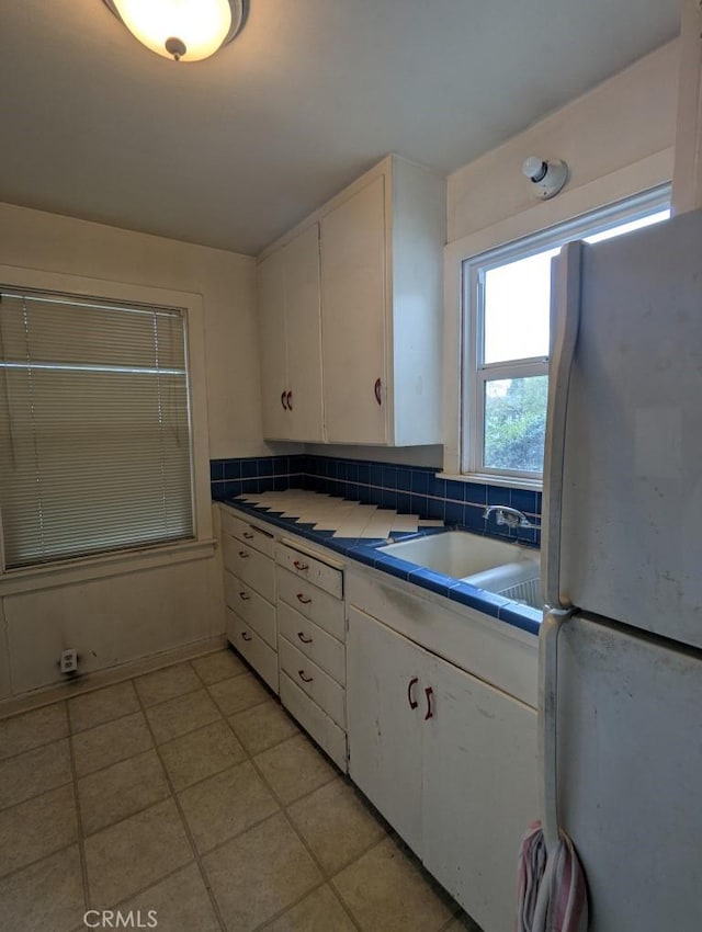 548 S Plumas St, Willows, CA 95988 - kitchen with freestanding refrigerator, tile countertops, white cabinets, light tile patterned floors, and backsplash