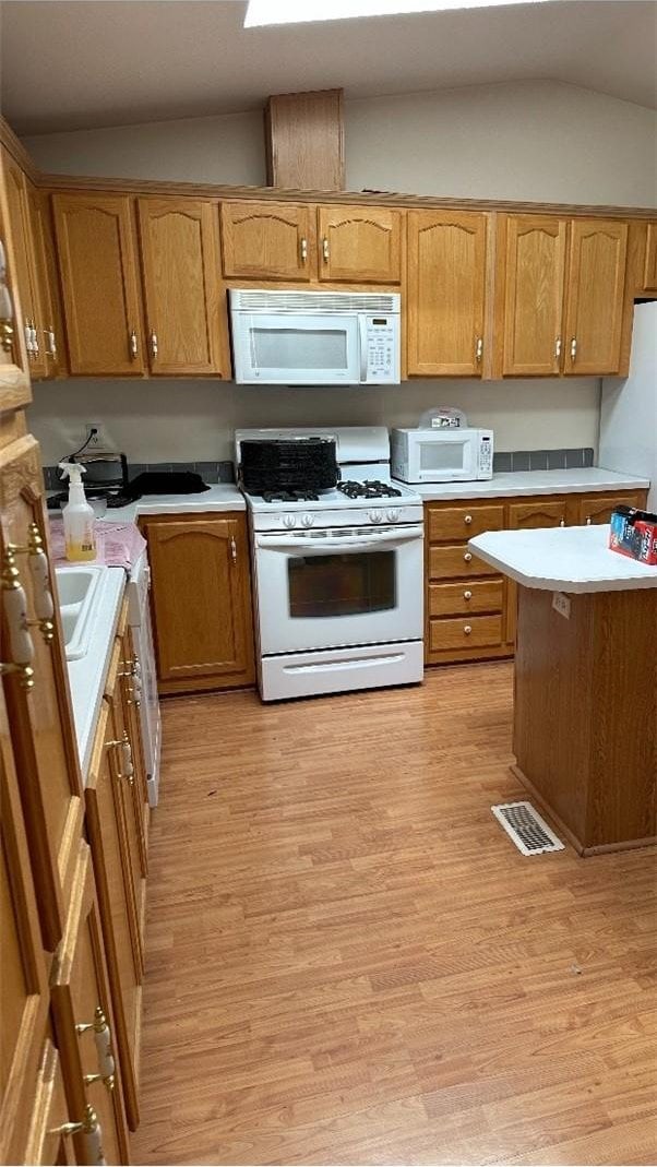 6117 Juniper Rd, Lake Isabella, CA 93240 - kitchen with white appliances, vaulted ceiling, light countertops, light wood finished floors, and brown cabinets