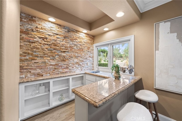 bar with recessed lighting, light wood-style flooring, and a sink