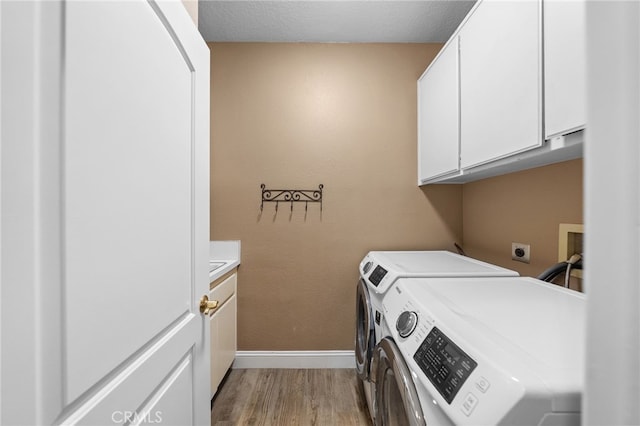 laundry area with washer and clothes dryer, light wood-type flooring, baseboards, and cabinet space