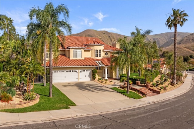 mediterranean / spanish home with a mountain view, a tile roof, driveway, and stucco siding
