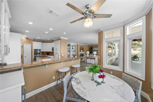 dining room featuring visible vents, a ceiling fan, crown molding, recessed lighting, and dark wood-type flooring