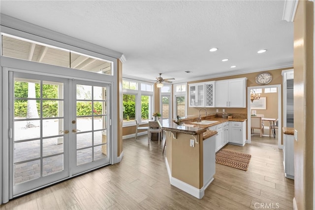 24240 Avenida De Marcia, Yorba Linda, CA 92887 - kitchen featuring a peninsula, white cabinets, ornamental molding, a breakfast bar, and french doors