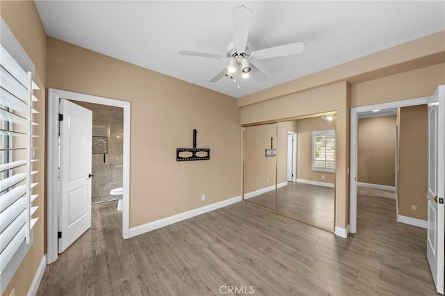 unfurnished bedroom with light wood-style floors, a closet, baseboards, and ensuite bathroom