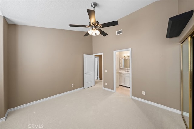 unfurnished bedroom with baseboards, ensuite bath, visible vents, high vaulted ceiling, and light colored carpet