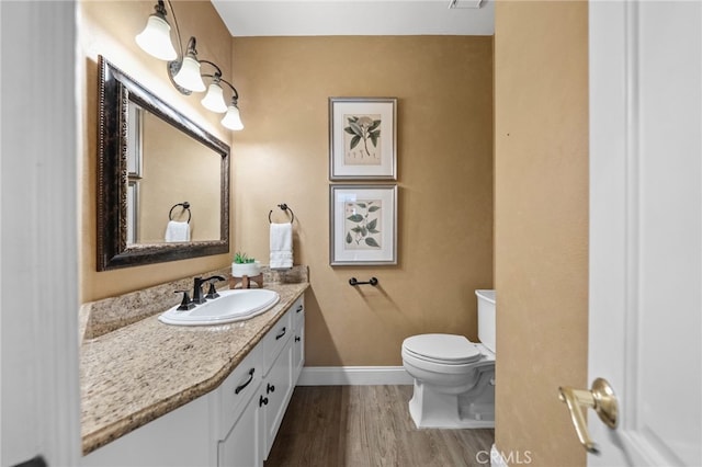 bathroom featuring toilet, vanity, wood finished floors, and baseboards