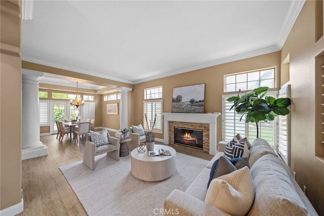 living area with ornate columns, an inviting chandelier, crown molding, and plenty of natural light
