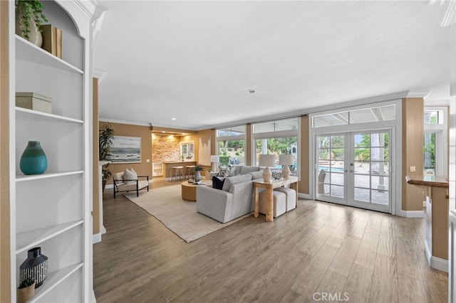 living area featuring crown molding, french doors, wood finished floors, and baseboards