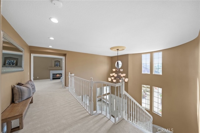 corridor with a notable chandelier, an upstairs landing, carpet, and recessed lighting