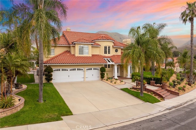 mediterranean / spanish home featuring a yard, stucco siding, a tile roof, a chimney, and driveway