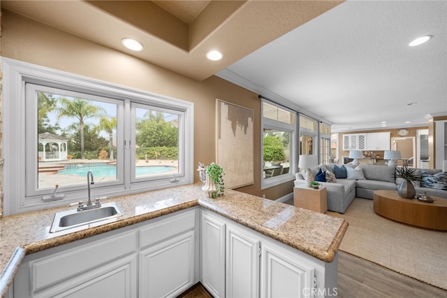 kitchen with a wealth of natural light, recessed lighting, white cabinets, and a sink