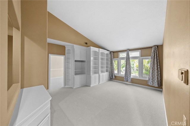 empty room featuring visible vents, carpet, and vaulted ceiling