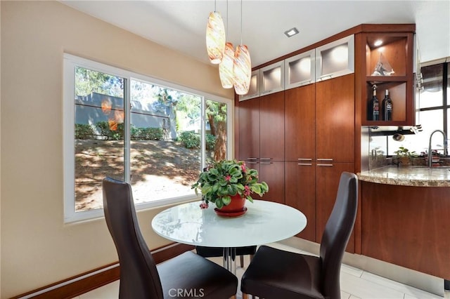 dining room with indoor wet bar, a healthy amount of sunlight, and light tile patterned flooring