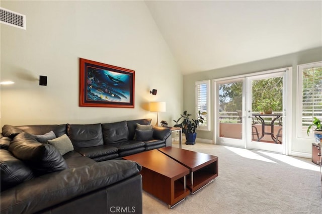 living area with light colored carpet, high vaulted ceiling, visible vents, and a wealth of natural light