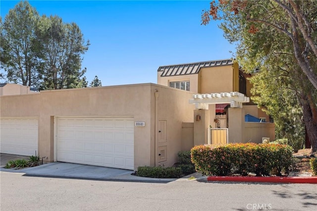 pueblo revival-style home featuring concrete driveway, stucco siding, and an attached garage