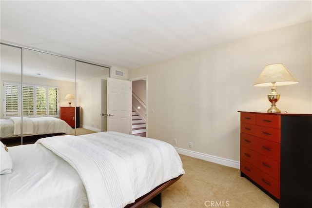 bedroom featuring visible vents, baseboards, a closet, and light colored carpet