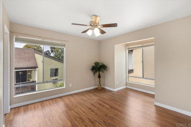 unfurnished room with baseboards, wood finished floors, and ceiling fan