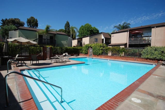 pool with a patio area and fence