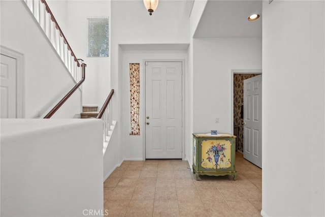 foyer featuring light tile patterned floors, baseboards, recessed lighting, and stairway
