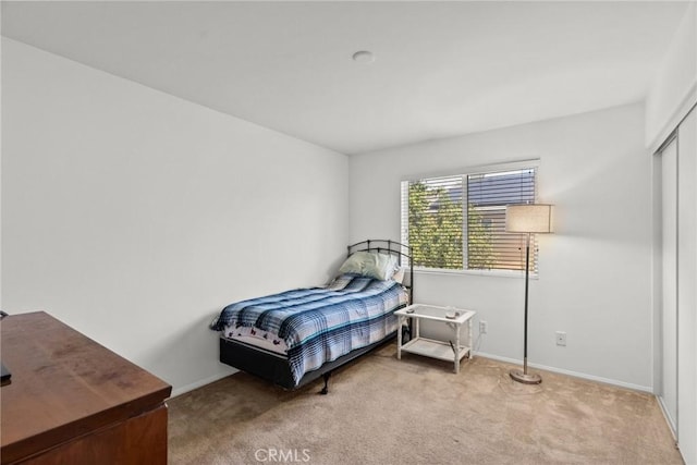 bedroom featuring light carpet, a closet, and baseboards