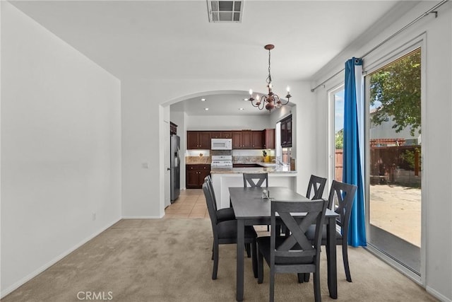 dining area with baseboards, a chandelier, visible vents, arched walkways, and light colored carpet