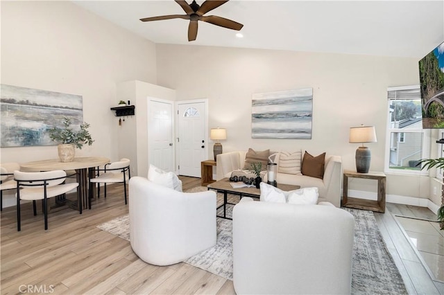 living room featuring lofted ceiling, light wood-style flooring, baseboards, and ceiling fan