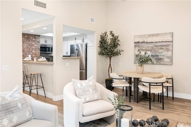 living room featuring baseboards, visible vents, and light wood-style flooring