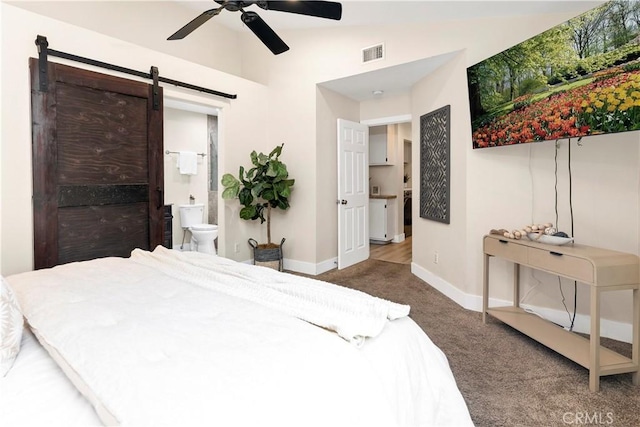 carpeted bedroom featuring a barn door, a ceiling fan, connected bathroom, baseboards, and visible vents