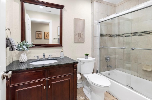 bathroom featuring toilet, visible vents, tile patterned flooring, vanity, and enclosed tub / shower combo