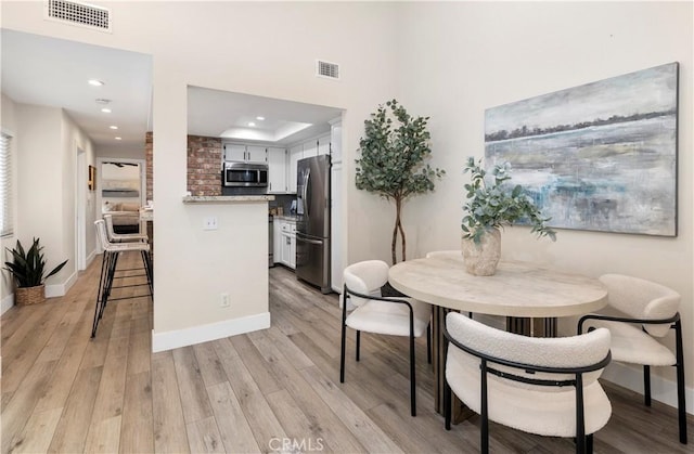 dining room with baseboards, light wood-style flooring, and visible vents