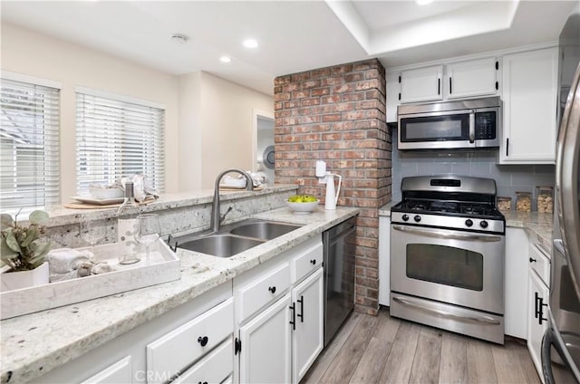 kitchen with light wood-type flooring, a sink, white cabinetry, and appliances with stainless steel finishes