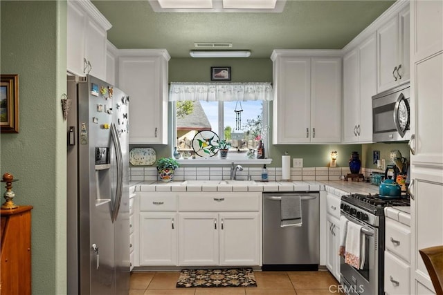 11 Maddie Ct, Chico, CA 95973 - kitchen with light tile patterned floors, white cabinets, a sink, tile counters, and stainless steel appliances