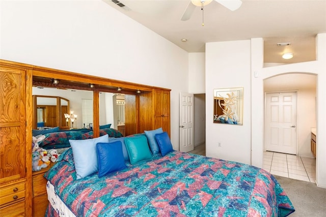 bedroom featuring tile patterned flooring, a ceiling fan, visible vents, carpet flooring, and arched walkways