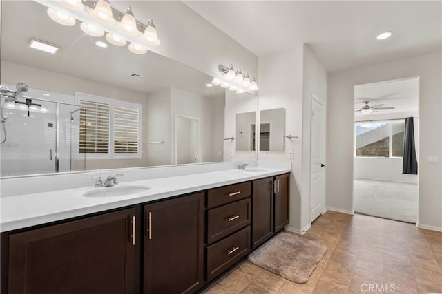 bathroom with a sink, baseboards, a shower stall, and double vanity